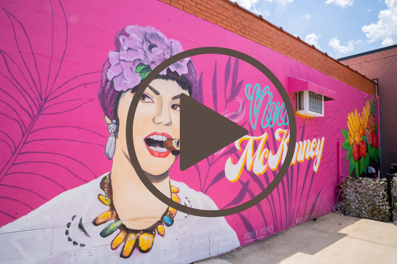 Pink street mural of a woman with flowers in her hair, from video work by Dark Rainbow Photo Video